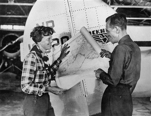 Penerbang Amelia Earhart dan navigator Fred Noonan berpose dengan peta Samudra Pasifik menunjukkan rencana rute yang akan mereka tempuh dalam penerbangan keliling dunia mereka.