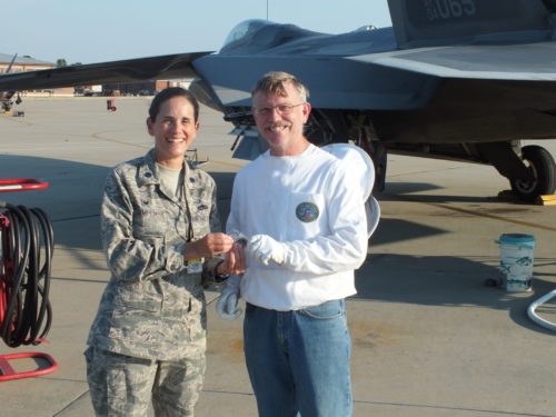 Lt. Col. Catherine M. Jumper, 192nd Aircraft Maintenance Squadron commander, presents Andy Westrich, U.S. Navy retired and local honey bee keeper, with a coin on June 11, 2016 at Joint Base Langley-Eustis, Virginia. Westrich was called to save and relocate a swarm of honey bees that landed on the exhaust nozzle of an F-22 Raptor engine. (U.S. Air Force courtesy photo)