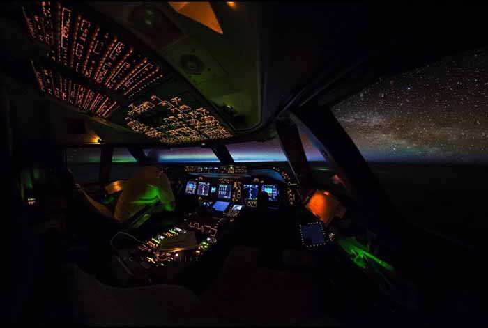 Penerbangan malam di atas Rusia utara, dengan cahaya utara dan Galaksi Bima Sakti terlihat dari jauh.